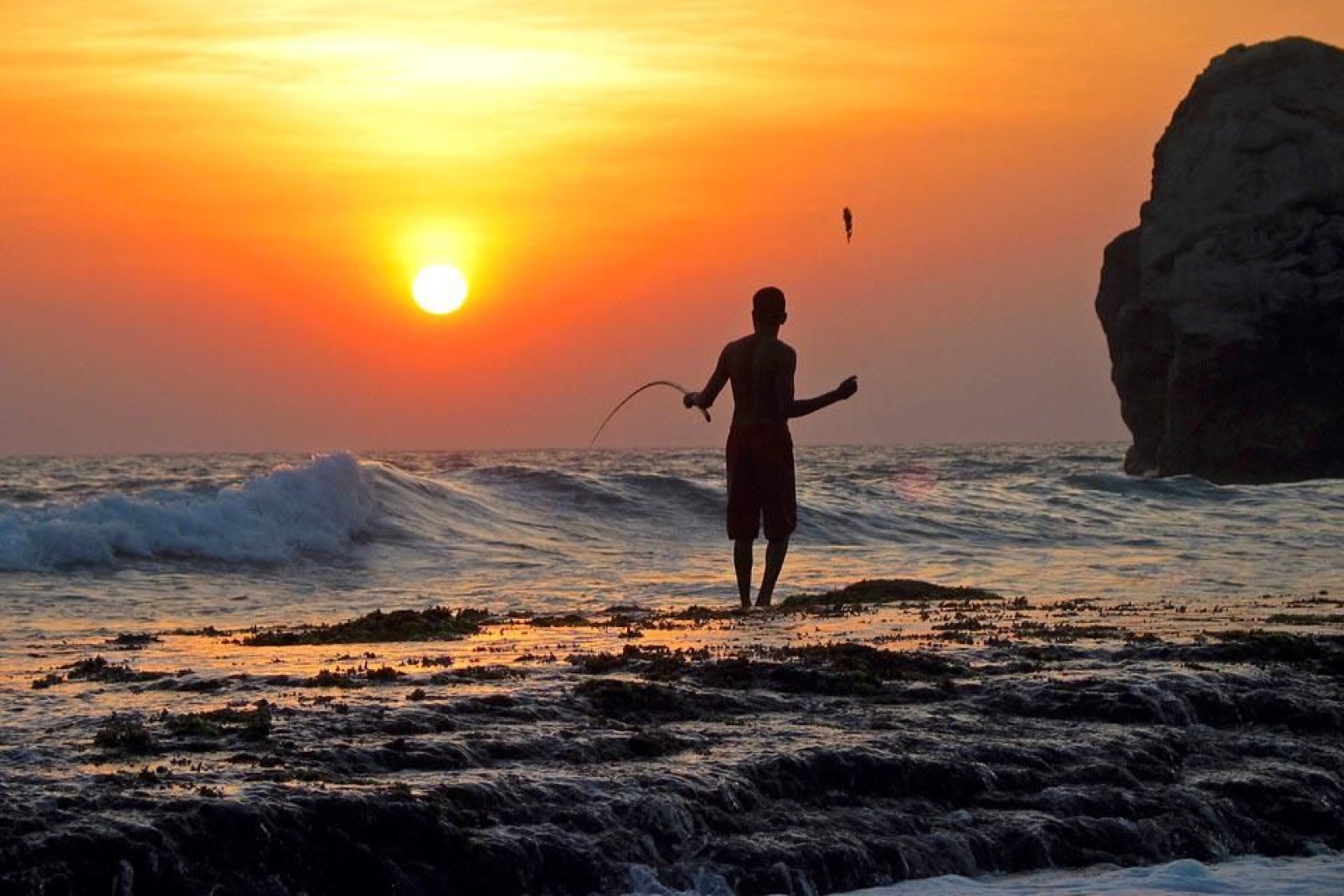 Ein Fischer wirft seine Angel aus und geniet den wunderschnen Sonnenuntergang vor Einbruch der Nacht.