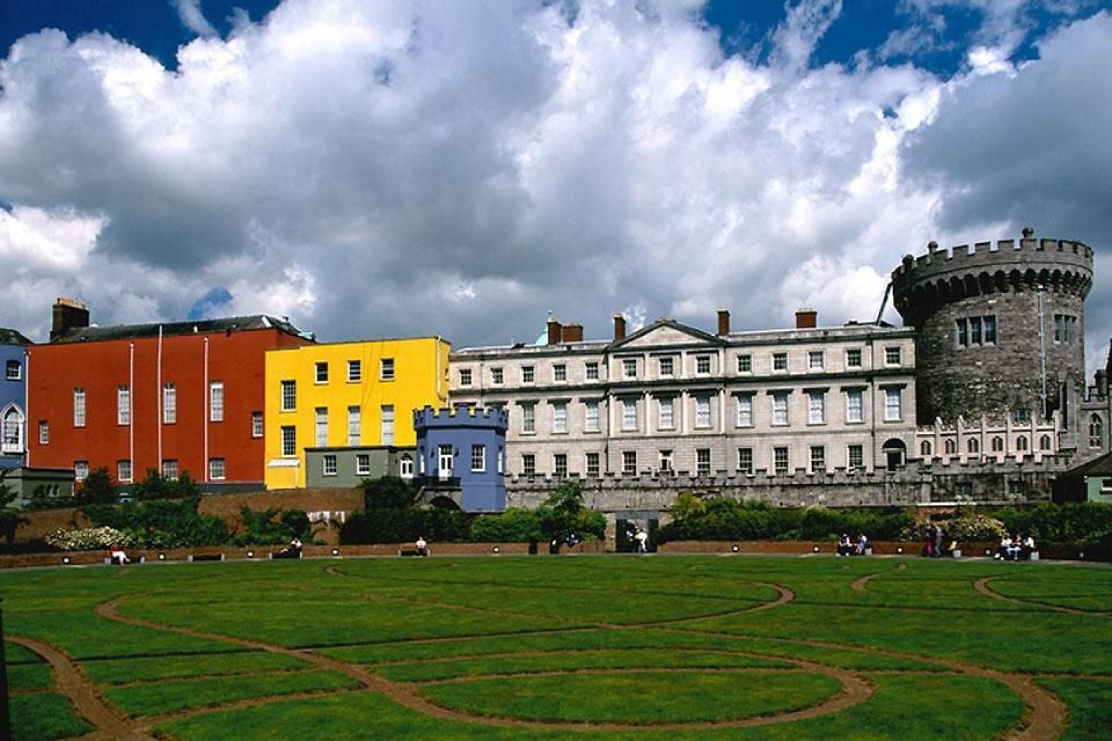 El castillo de Dublín, rodeado de coloridas construcciones modernas, se eleva por encima de un magnífico y cuidado jardín.