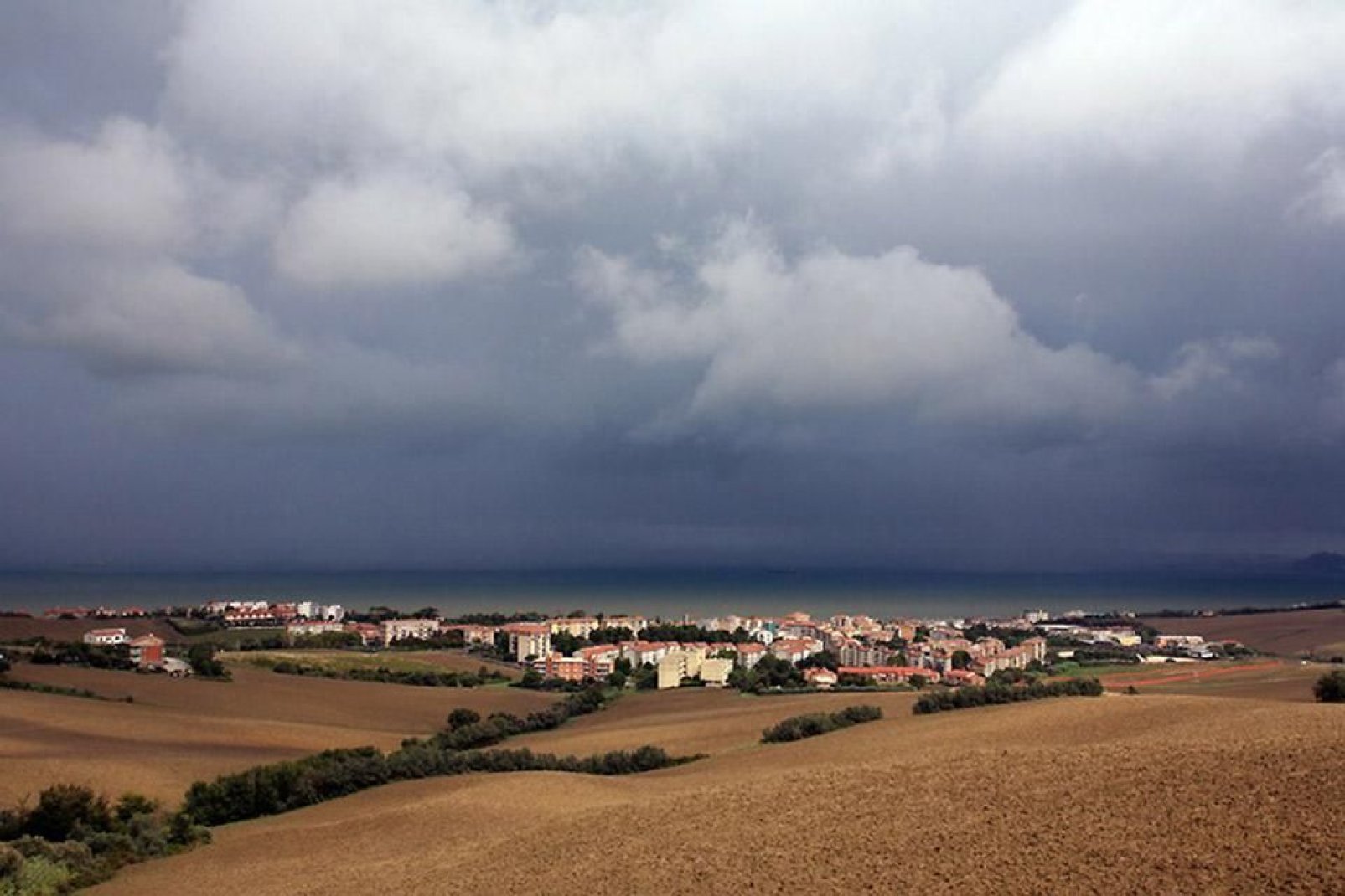Ein Panoramablick über die Küste von Ancona vom Hinterland aus: die Farbe der Erde hebt sich vom dunkelblauen Meerwasser der Adria ab.