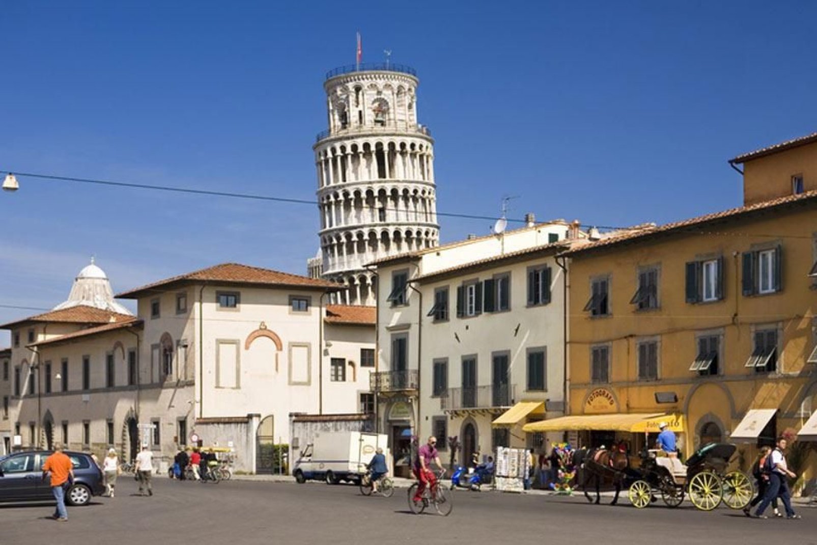 The top of the tower can be seen rising above the houses in the centre of Pisa