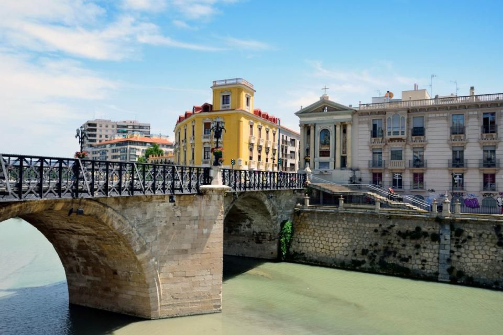 The river crosses the city from west to east, several bridges of different styles span it.
