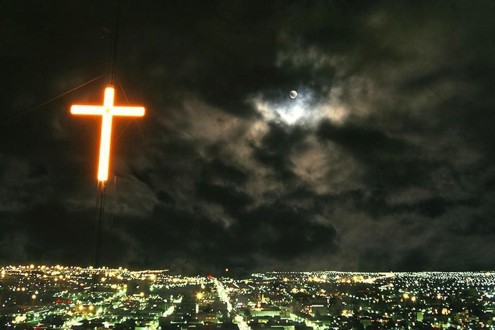 Une croix rose illumine la ville de Bloemfontein pendant la nuit.