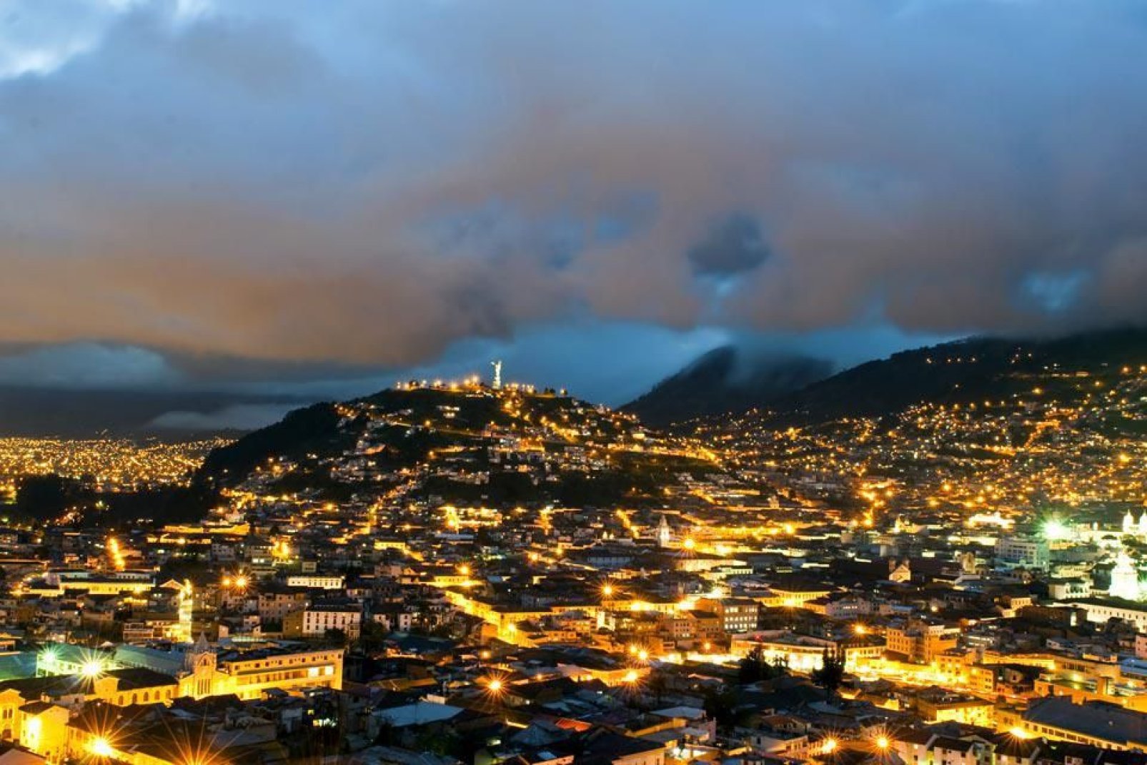 Quito es una ciudad rodeada por volcanes y colinas verdes, un panorama que destaca tanto de día como de noche.